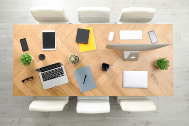 Photo of Modern office table with devices and chairs, top view