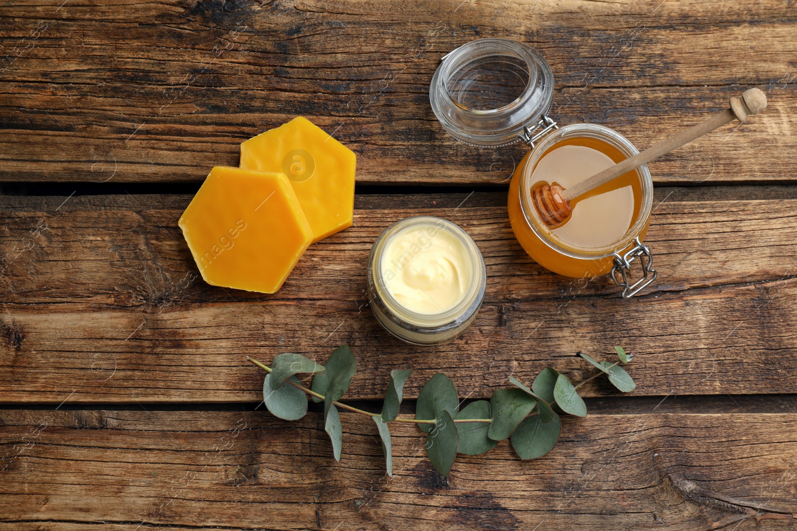 Photo of Natural beeswax, cream, honey and eucalyptus on wooden table, flat lay