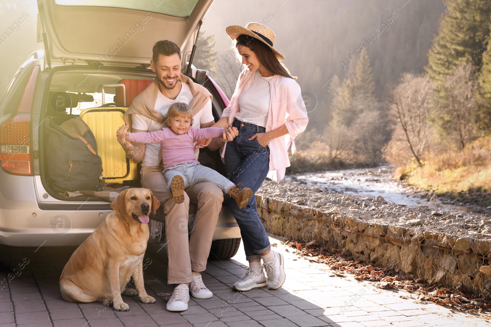 Photo of Parents, their daughter and dog near car outdoors, space for text. Family traveling with pet