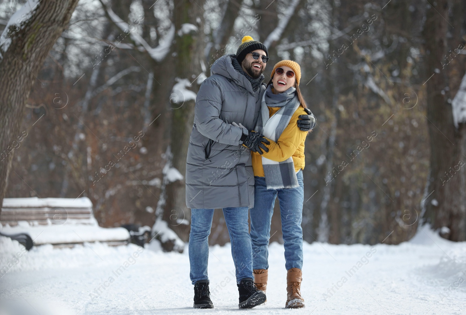 Photo of Happy young couple walking in snowy park on winter day