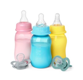 Feeding bottles with milk and pacifiers on white background