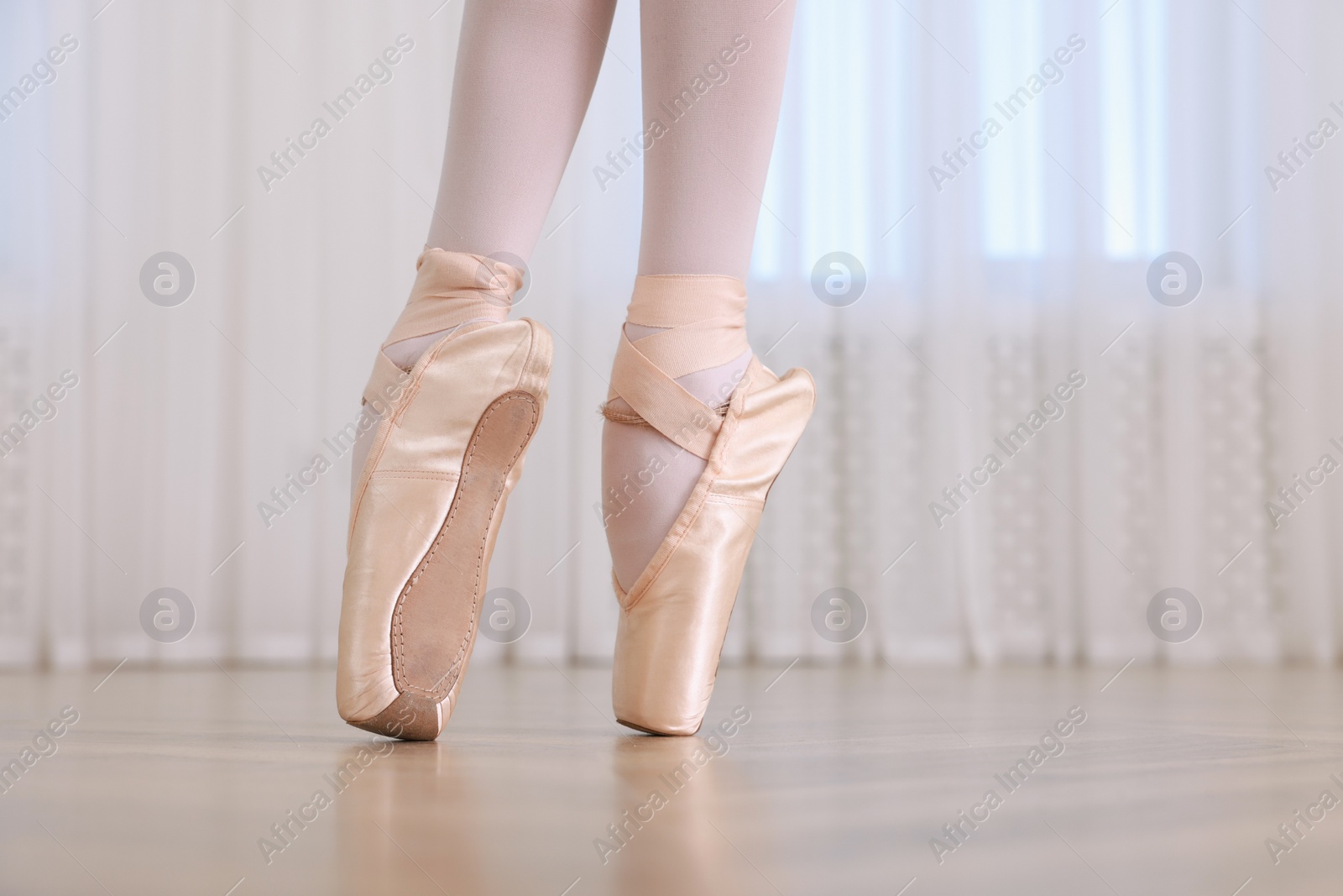 Photo of Little ballerina practicing dance moves in studio, closeup of legs. Space for text