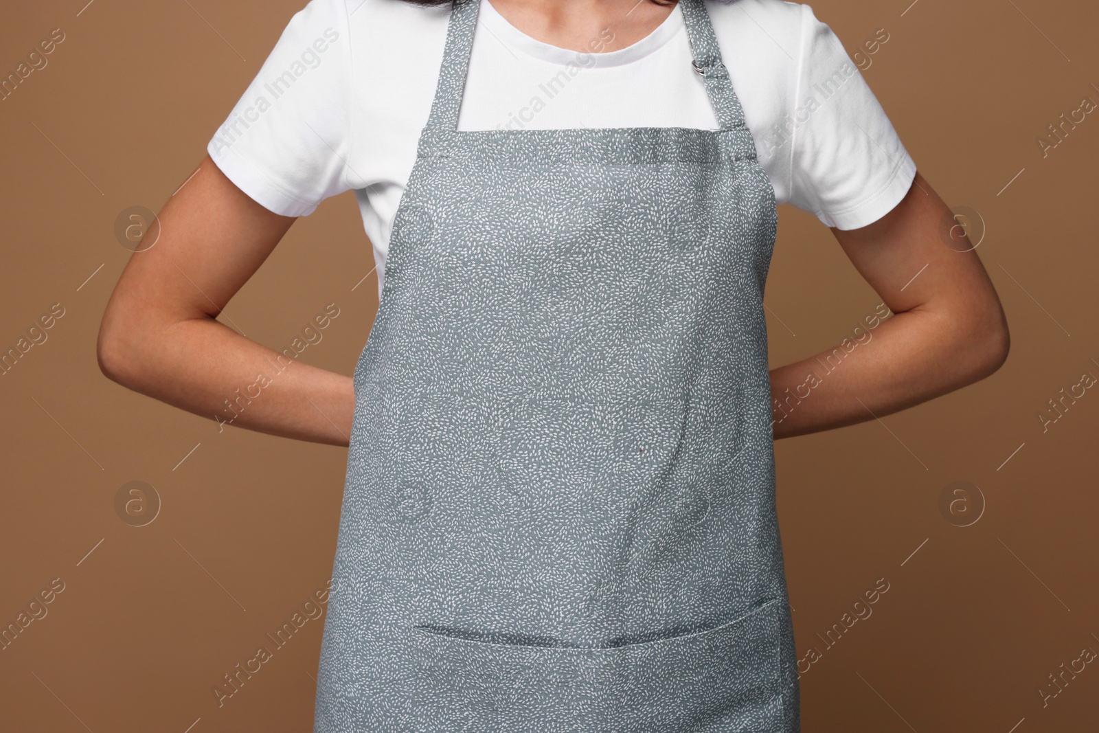 Photo of Woman wearing kitchen apron on brown background, closeup. Mockup for design