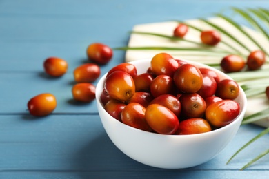 Photo of Palm oil fruits in bowl on blue wooden table, closeup