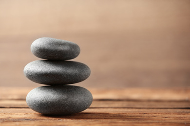 Photo of Stack of spa stones on wooden table. Space for text