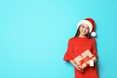 Young woman with Christmas gift on color background