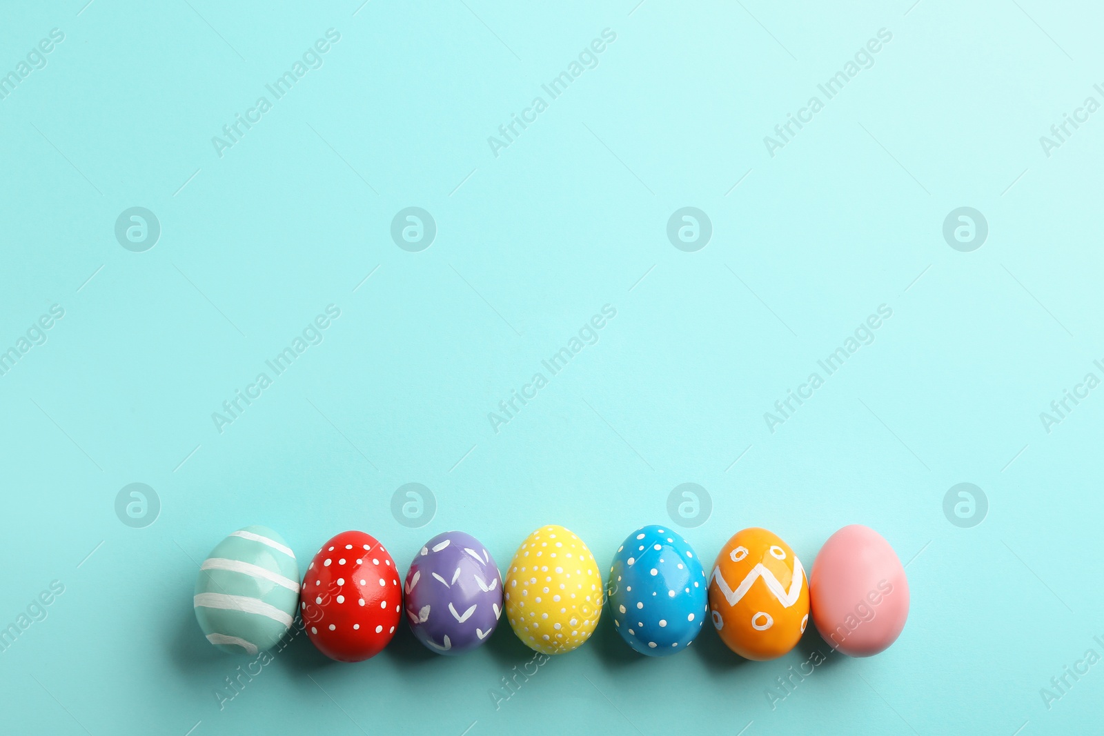 Photo of Flat lay composition of painted Easter eggs on color background, space for text