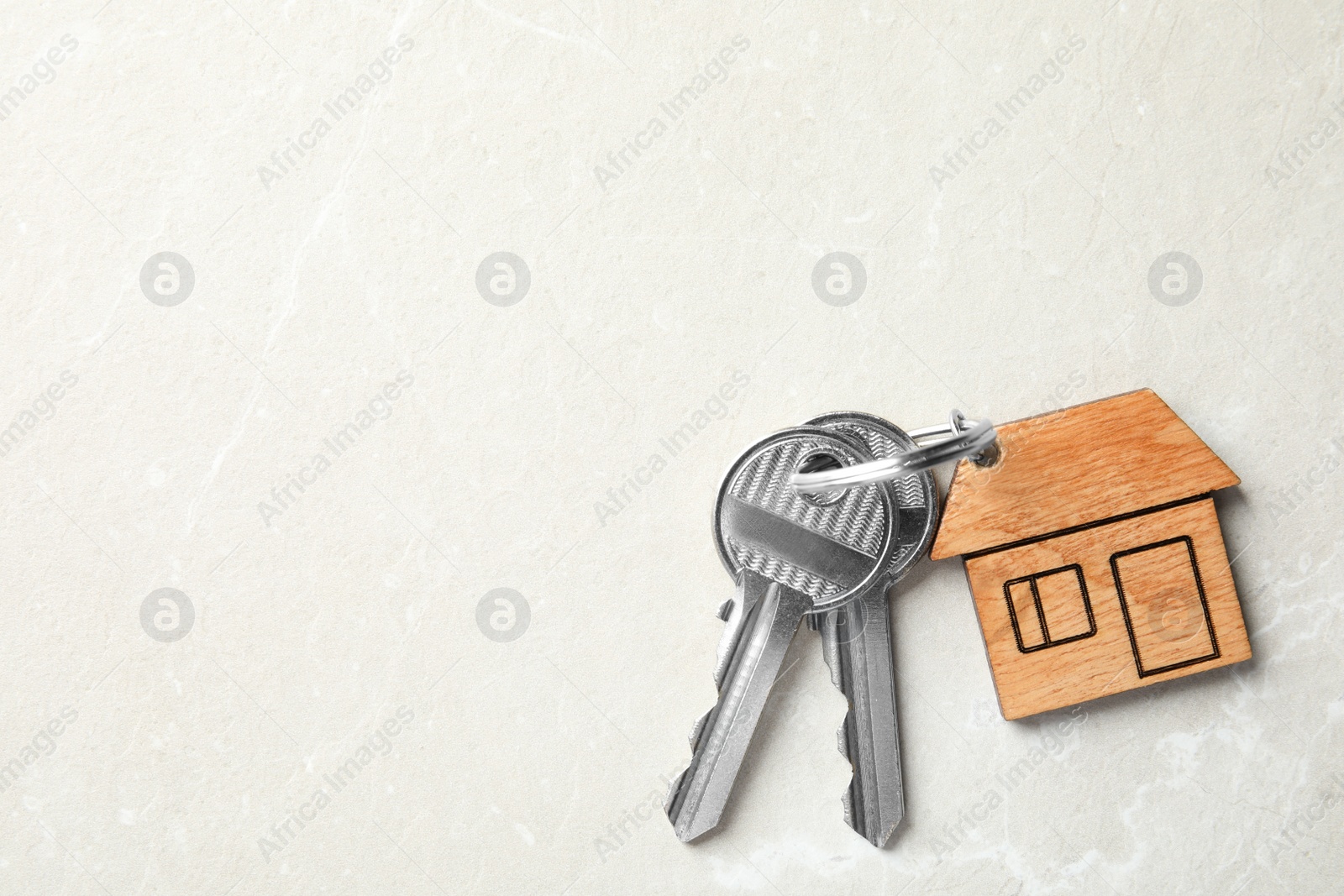 Photo of House keys with trinket on light background, top view. Space for text