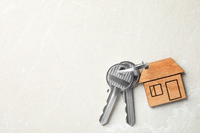 House keys with trinket on light background, top view. Space for text