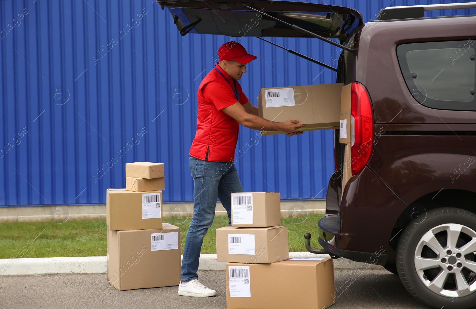 Photo of Courier loading packages in car trunk outdoors