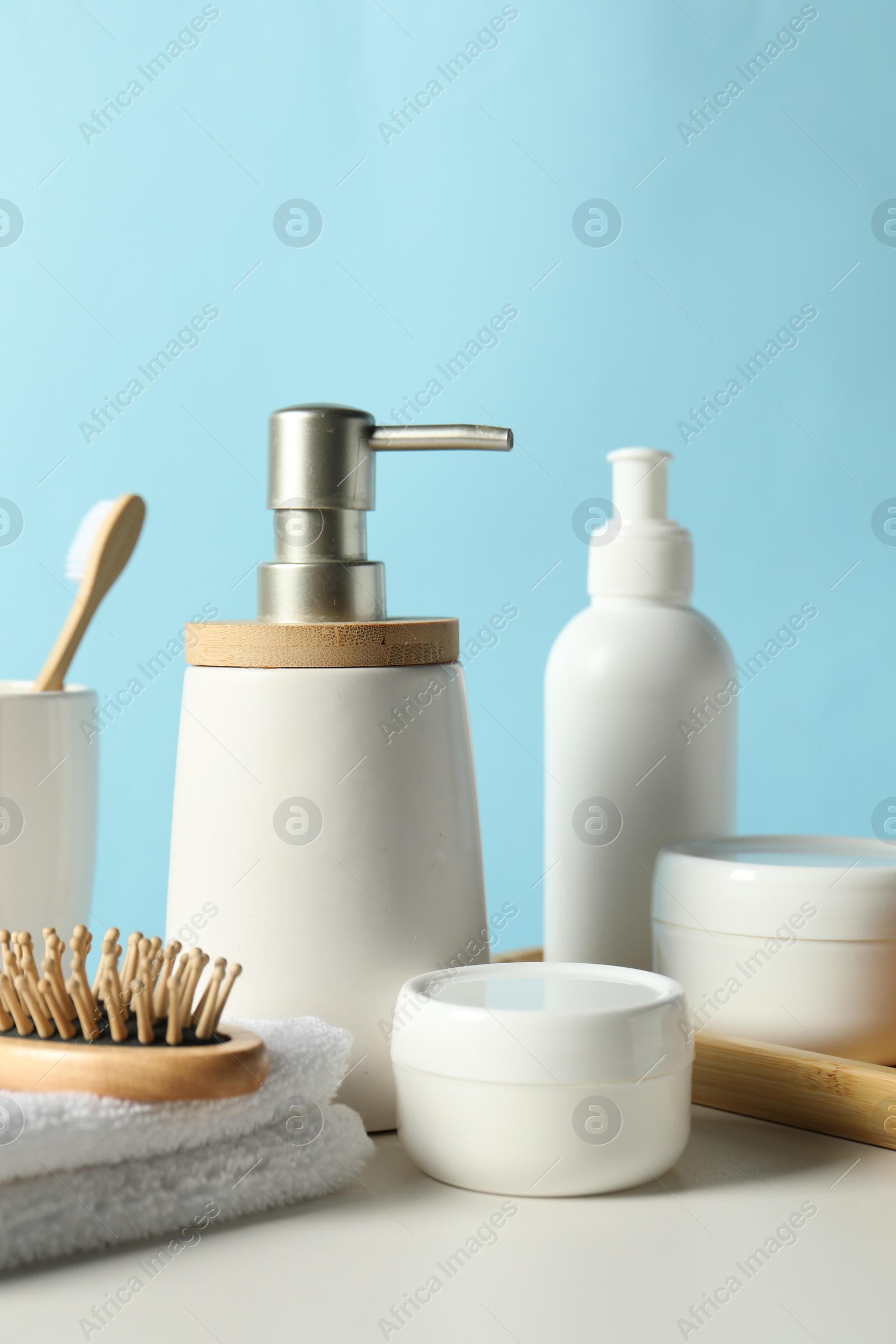 Photo of Different bath accessories on white table against light blue background