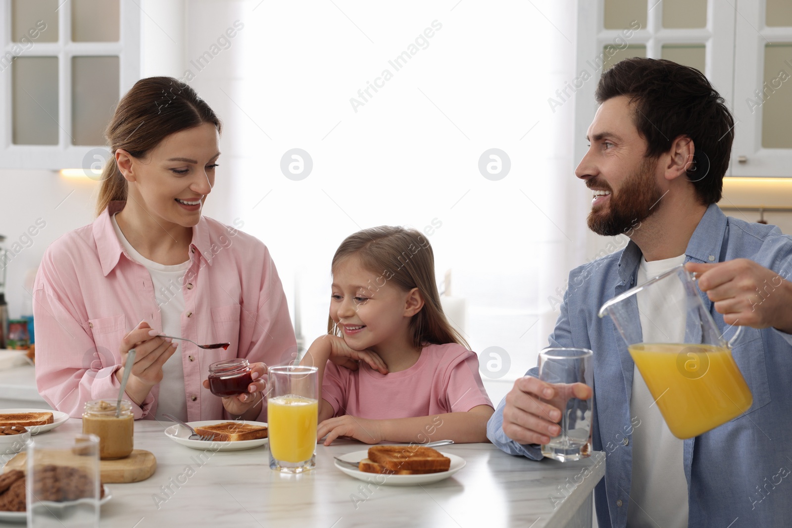 Photo of Happy family having breakfast at table in kitchen