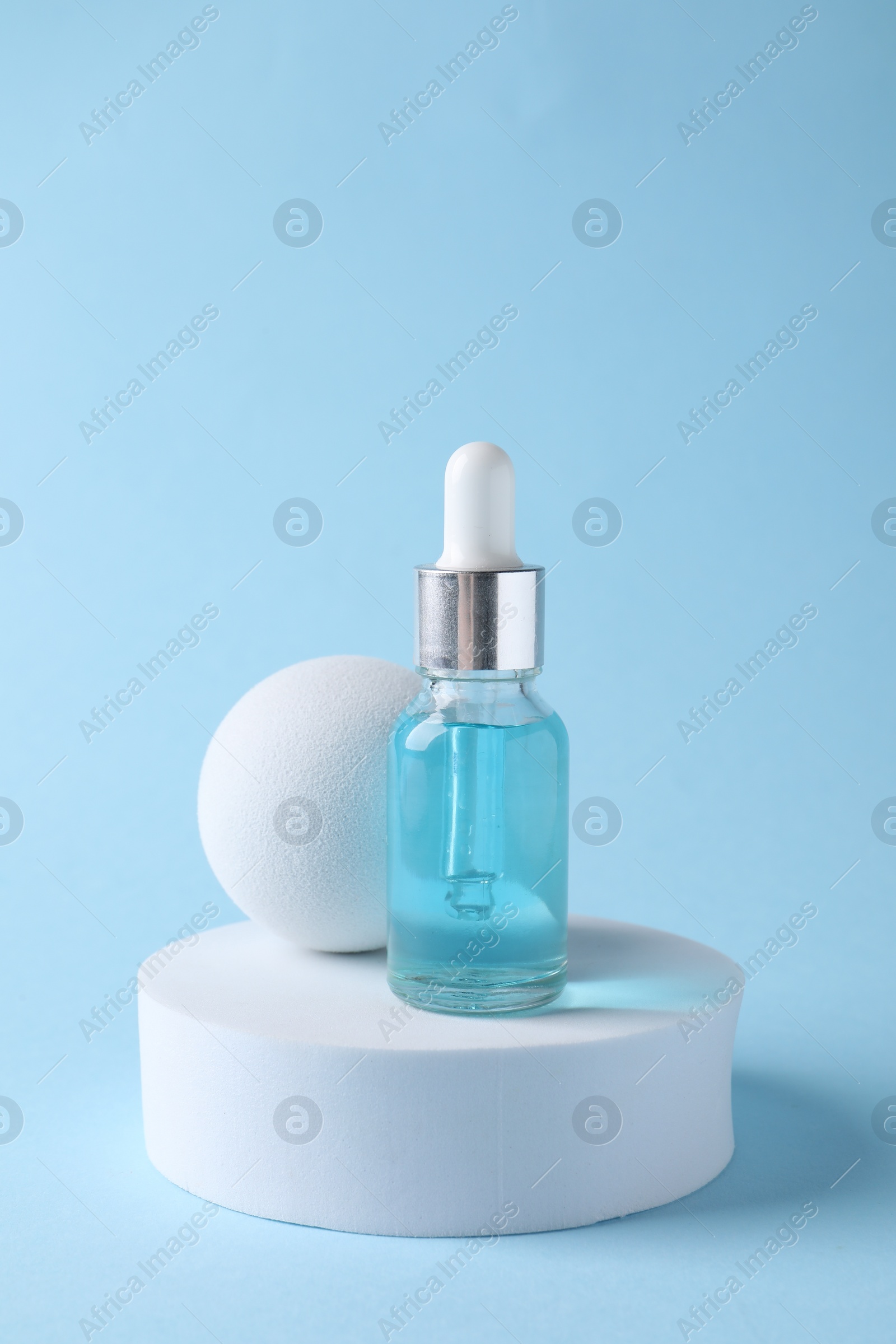 Photo of Presentation of bottle with cosmetic serum on light blue background