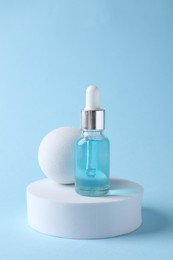 Presentation of bottle with cosmetic serum on light blue background