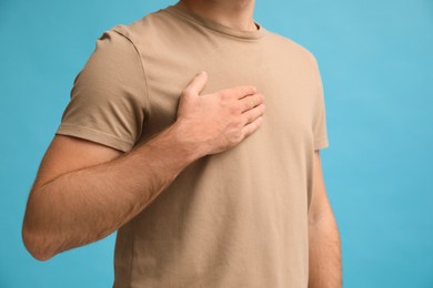 Photo of Man holding hand near chest on turquoise background, closeup