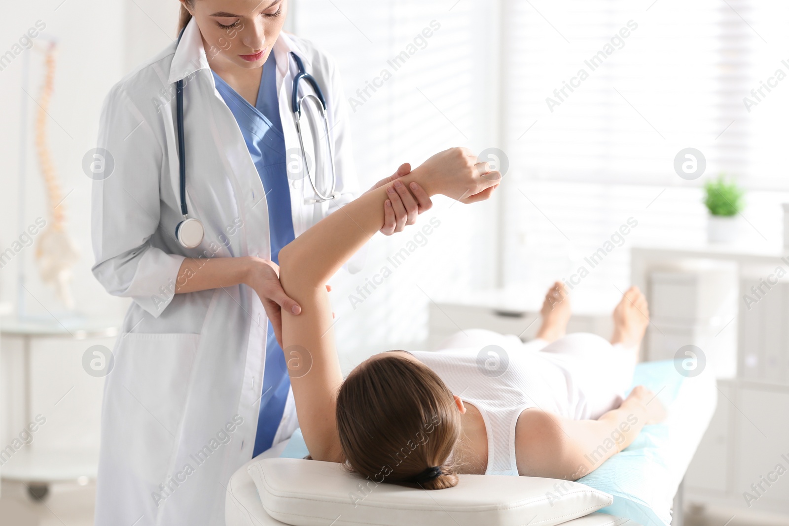 Photo of Female orthopedist examining patient's arm in clinic