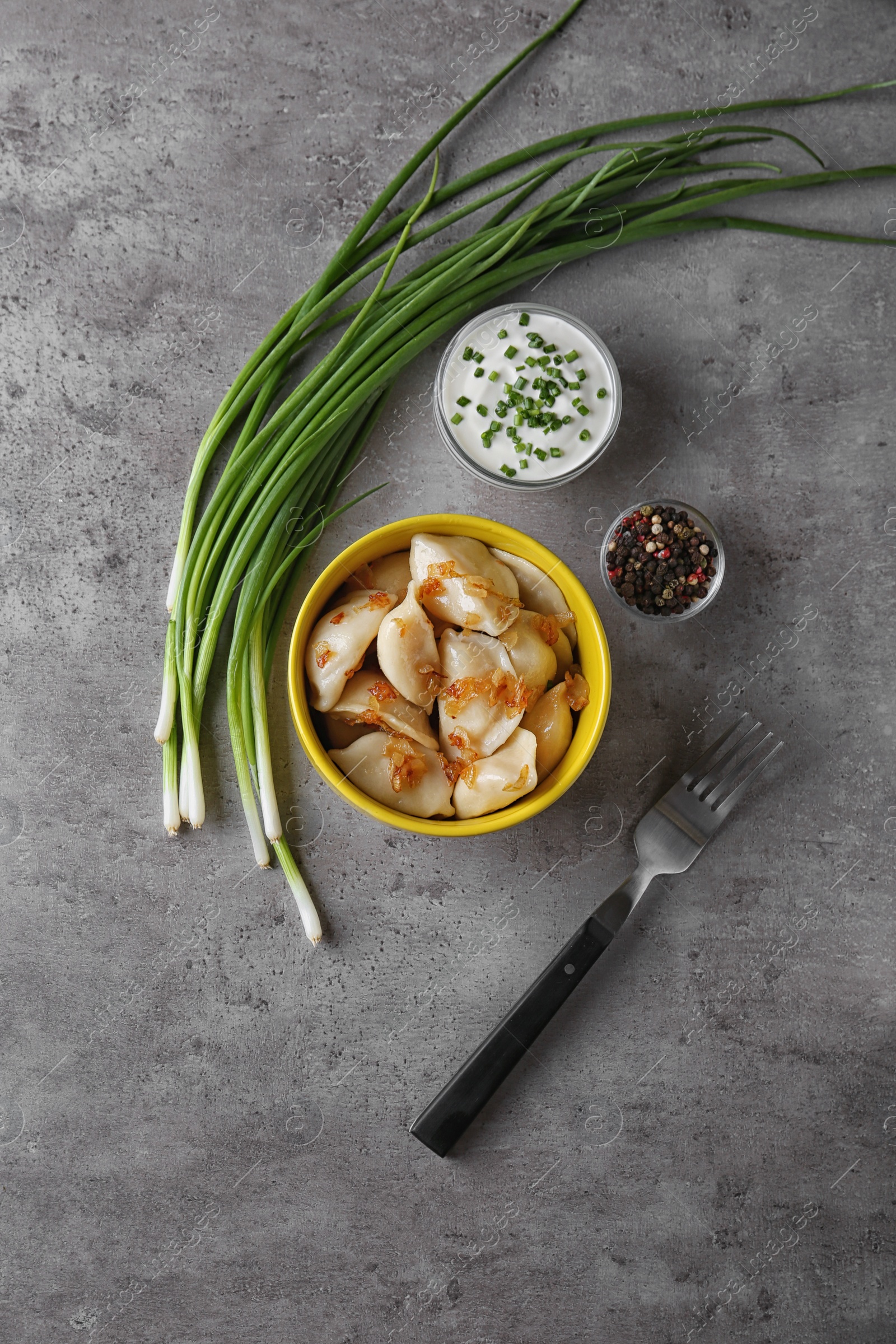 Photo of Delicious cooked dumplings with fried onion on grey table, flat lay