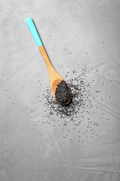 Photo of Spoon with poppy seeds on grey background, top view