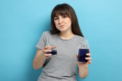 Photo of Young woman using mouthwash on light blue background