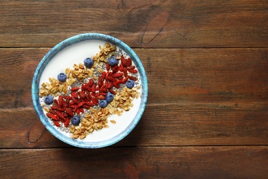 Smoothie bowl with goji berries on wooden table, top view. Space for text