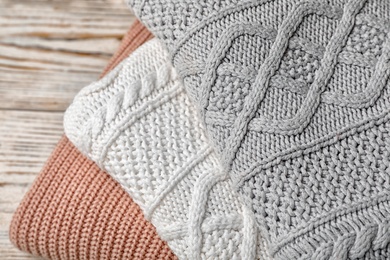 Photo of Stack of folded knitted sweaters on table, closeup