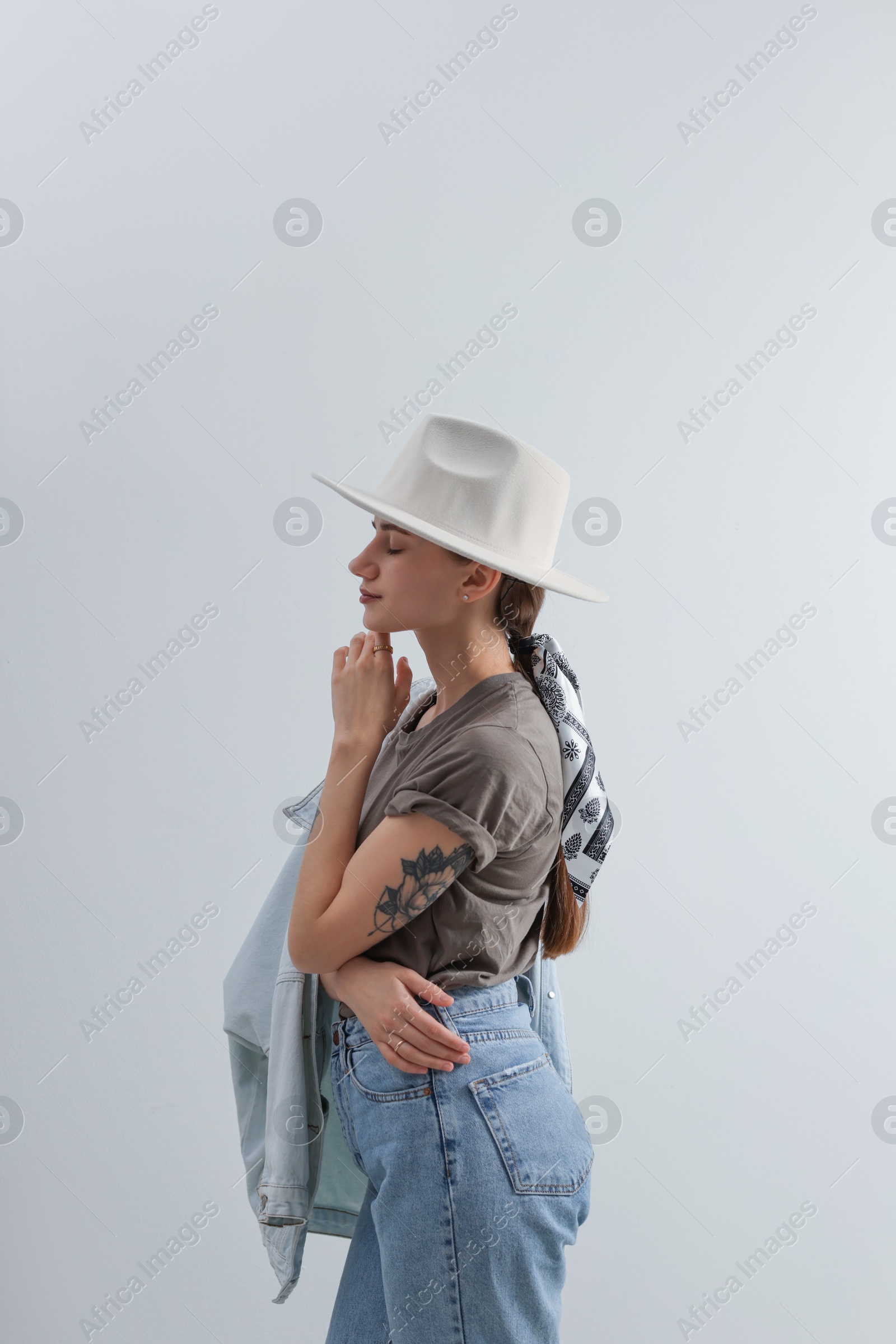 Photo of Young woman with hat and stylish bandana on light background