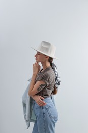 Young woman with hat and stylish bandana on light background