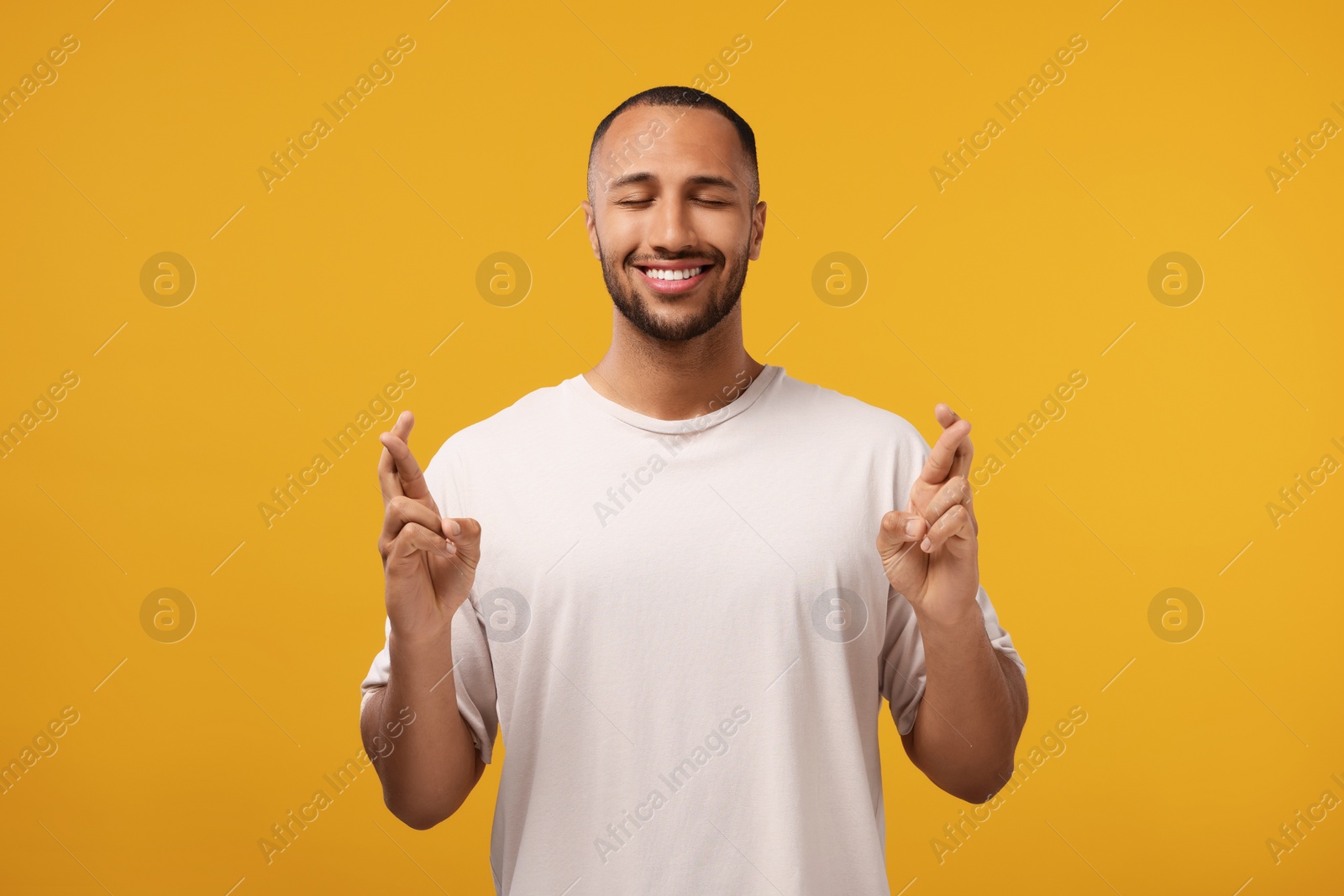 Photo of Happy man crossing his fingers on orange background