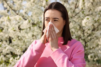 Woman with napkin suffering from seasonal allergy on spring day