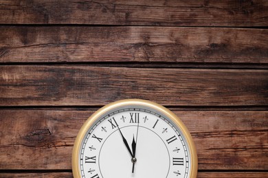 Photo of Clock showing five minutes until midnight on wooden table, top view with space for text. New Year countdown