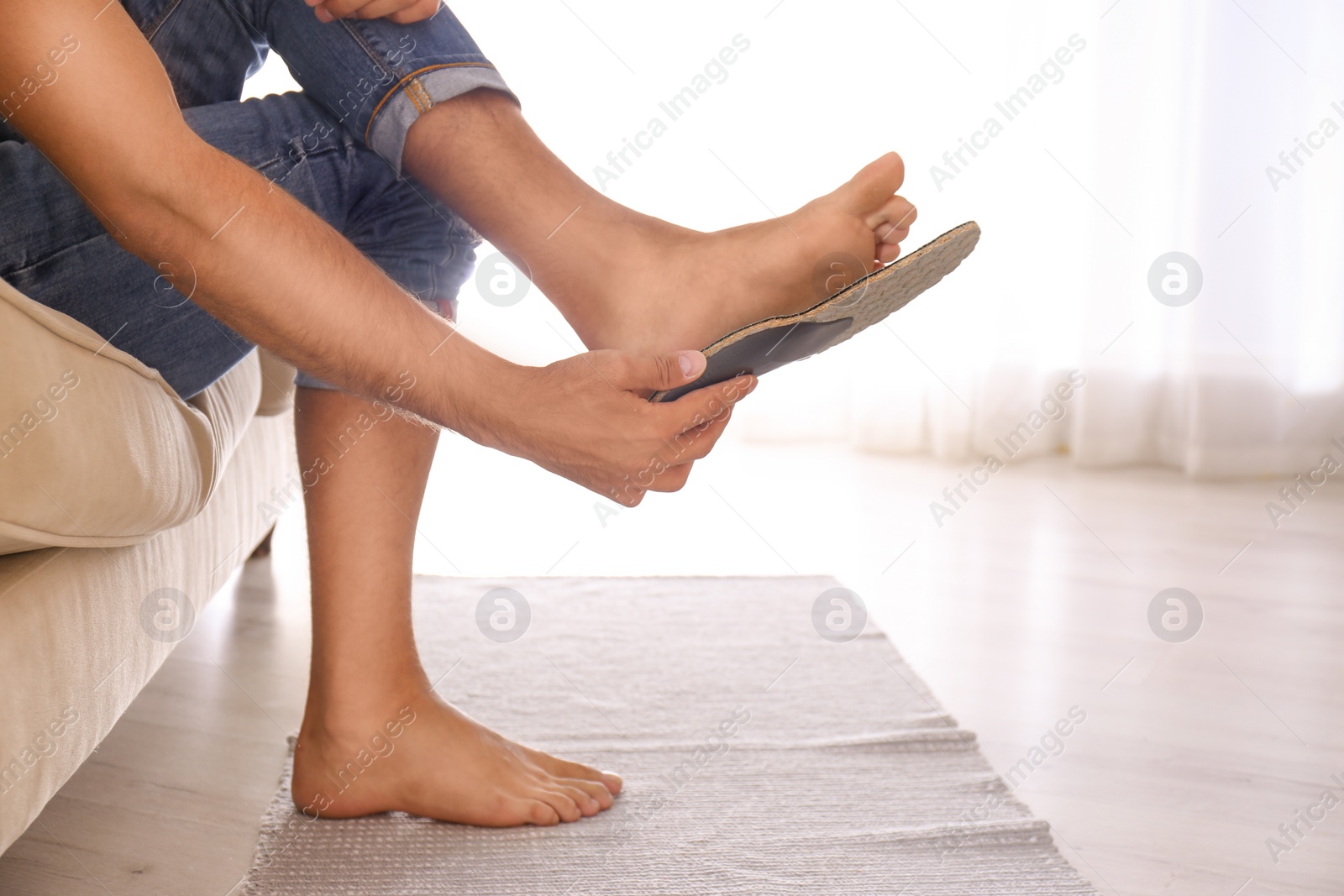 Photo of Man fitting orthopedic insole at home, closeup