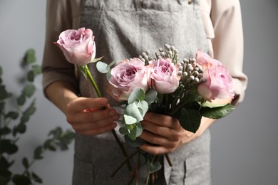 Photo of Florist creating beautiful bouquet with roses indoors, closeup