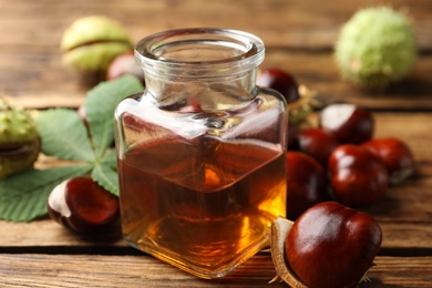 Chestnuts and jar of essential oil on wooden table