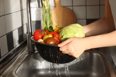 Photo of Woman washing different vegetables in metal colander, closeup