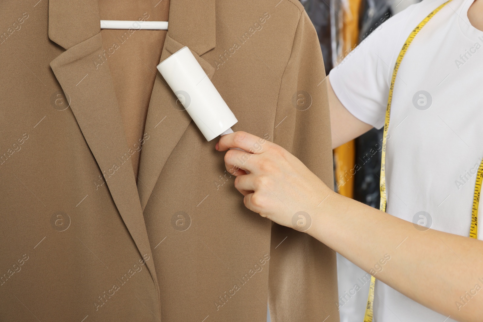 Photo of Woman using adhesive lint roller indoors, closeup. Dry-cleaning service