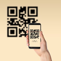 Woman scanning QR code with smartphone on beige background, closeup