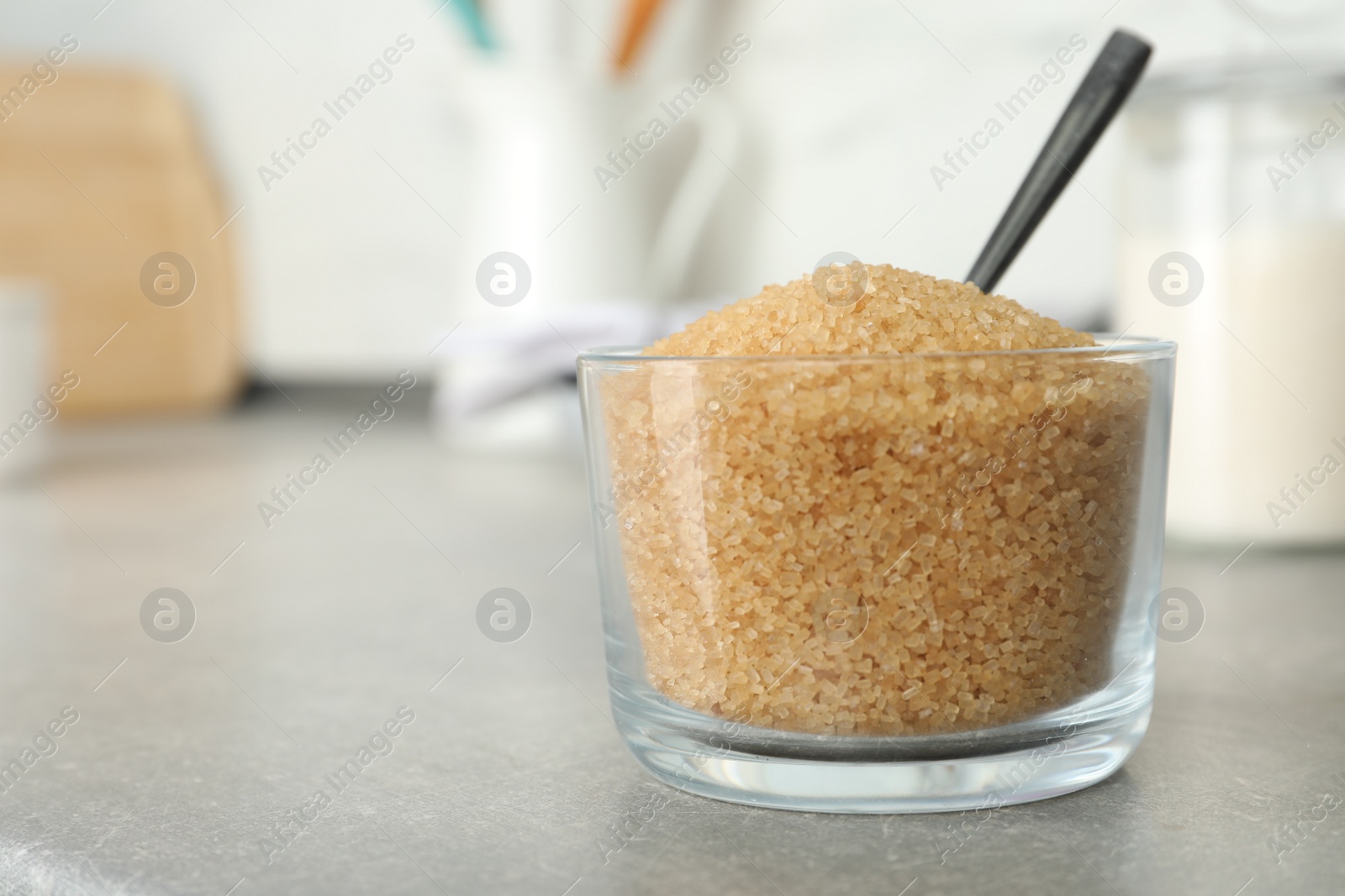 Photo of Glass bowl with brown sugar on grey table