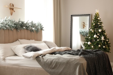 Photo of Beautiful decorated Christmas tree with fairy lights in bedroom interior