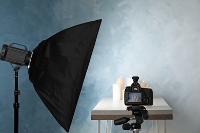 Photo of Professional photo equipment and candles on table against color wall