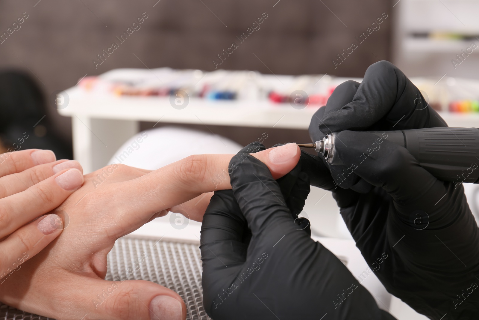 Photo of Professional manicurist working with client in salon, closeup