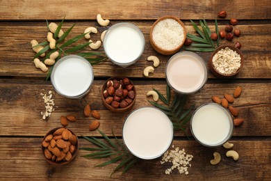 Photo of Different vegan milks and ingredients on wooden table, flat lay