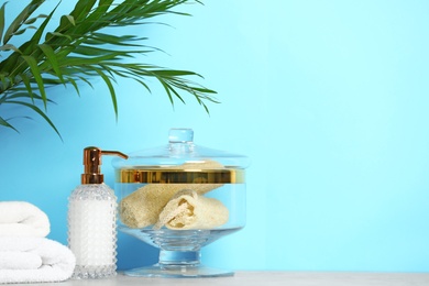 Photo of Composition of glass jar with luffa sponges on table near blue wall. Space for text
