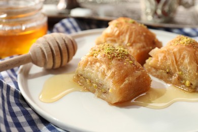 Photo of Delicious sweet baklava with pistachios and honey on table, closeup