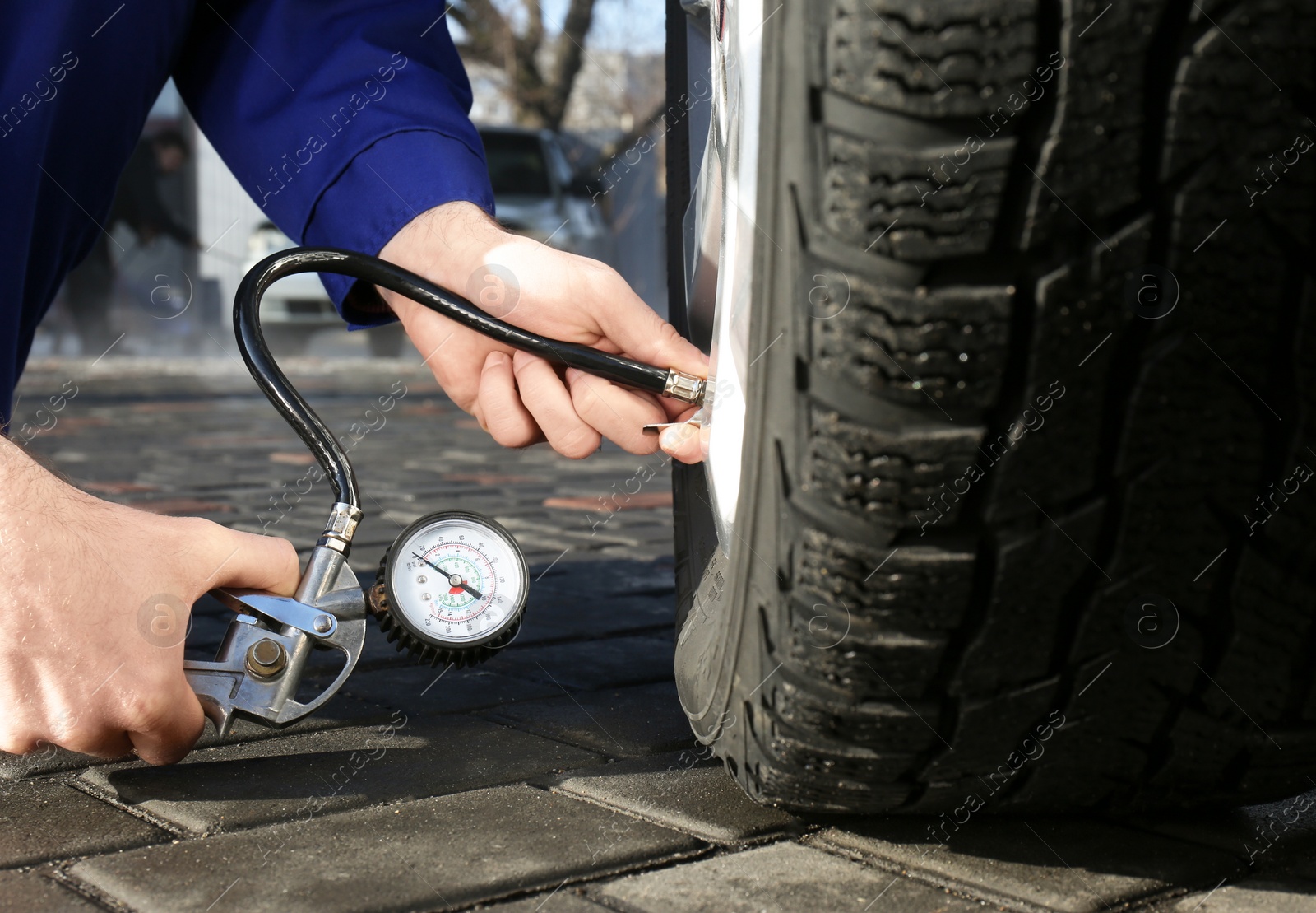 Photo of Mechanic checking tire air pressure at car service, closeup