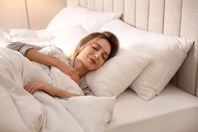 Photo of Woman under warm white blanket sleeping in bed indoors