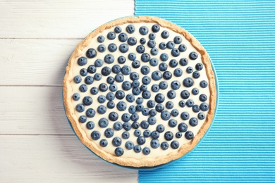 Photo of Tasty cake with blueberry on wooden background, top view