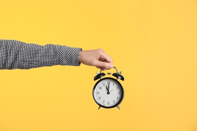 Photo of Young woman holding clock on color background. Time management