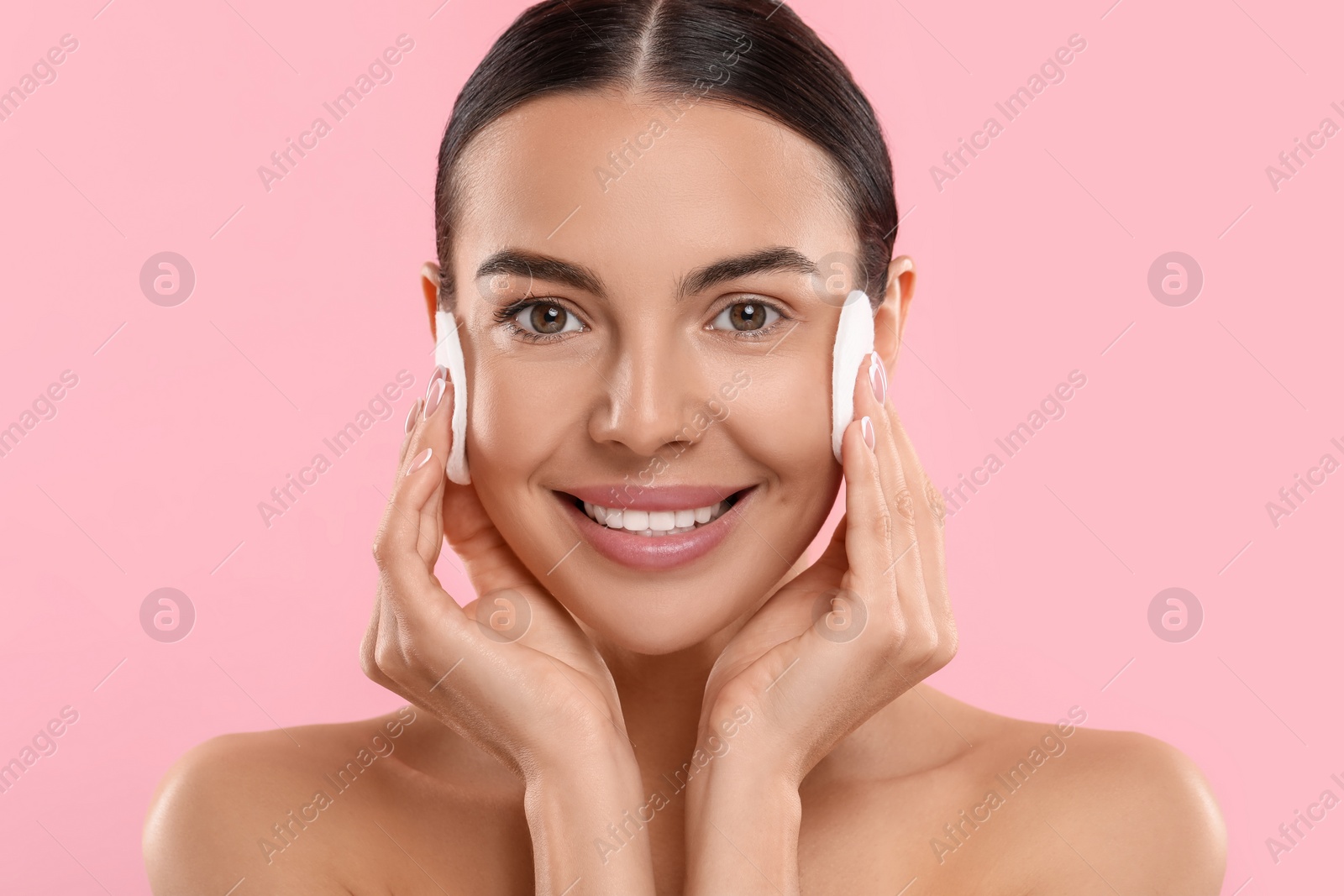 Photo of Beautiful woman removing makeup with cotton pads on pink background