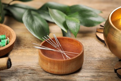 Photo of Bowl with acupuncture needles on wooden table