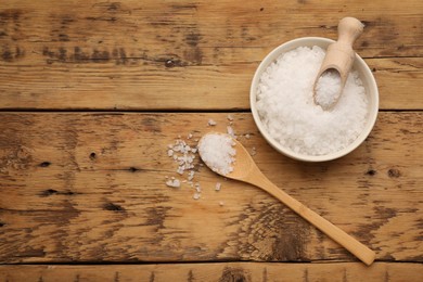 Photo of Bowl, spoon and scoop with sea salt on wooden table, flat lay. Space for text